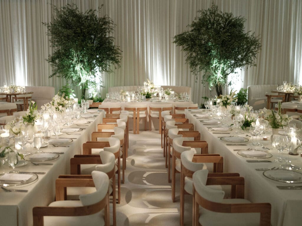 Outdoor wedding ceremony setup at The Ritz-Carlton Bacara in Santa Barbara with natural wood chairs, Mediterranean urns, and lush greenery overlooking the ocean.
